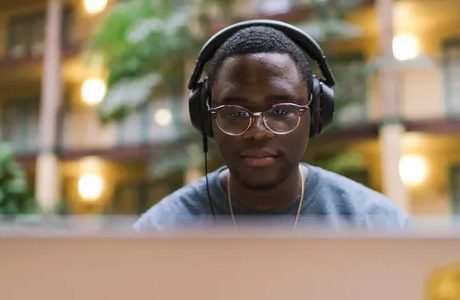 A man wearing headphones and sitting at his computer.